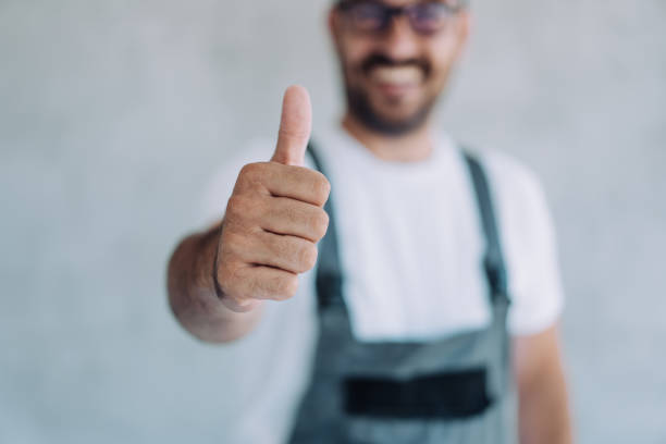 A plumber gives a thumbs up to a camera.